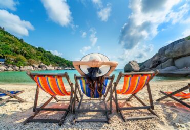 Woman with hat sitting on chairs beach in beautiful tropical beach. Woman relaxing on a tropical beach at Koh Nangyuan island.
